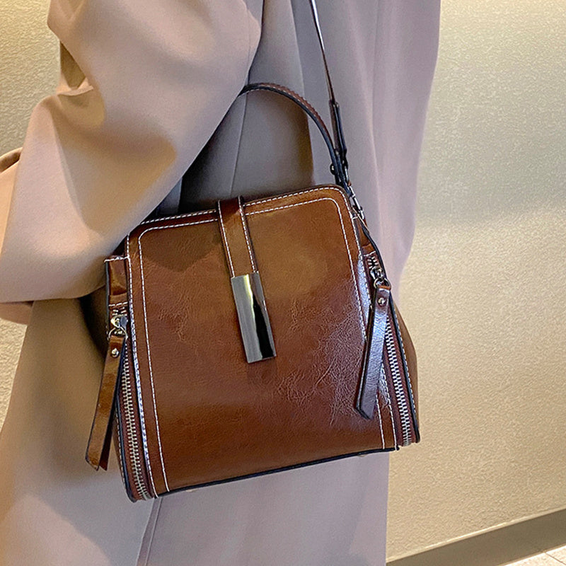 Stylish leather shoulder bag for women with removable strap, zipper closure, and edge paint detail. Available in black, coffee, and light brown.