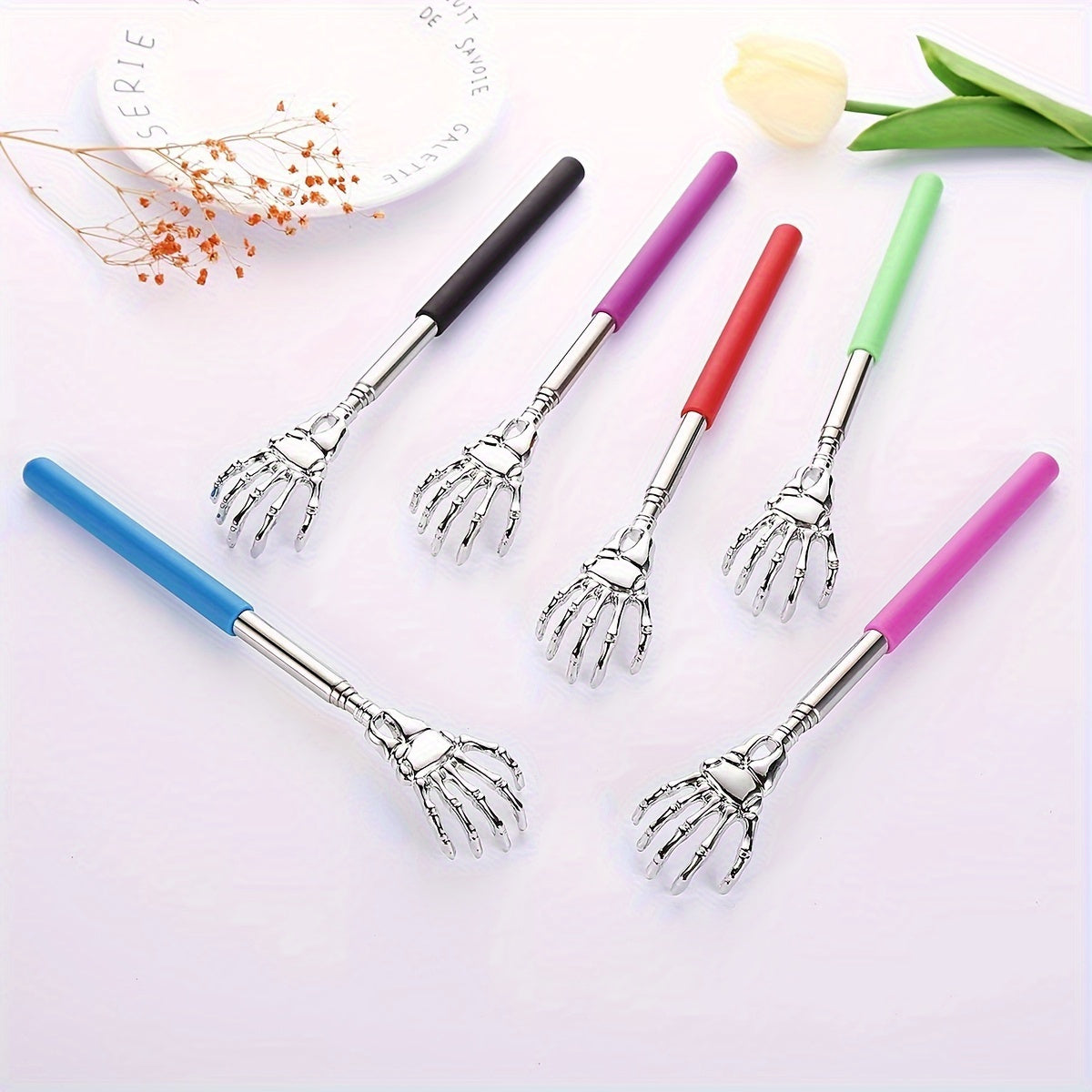 Extendable stainless steel back scratcher and massager with spooky skeleton hand design, adjustable length of 19.05cm to 69.85cm. Portable and durable construction.