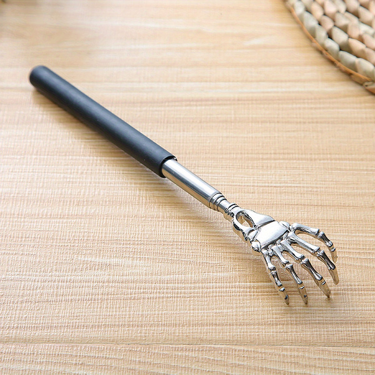 Extendable stainless steel back scratcher and massager with spooky skeleton hand design, adjustable length of 19.05cm to 69.85cm. Portable and durable construction.