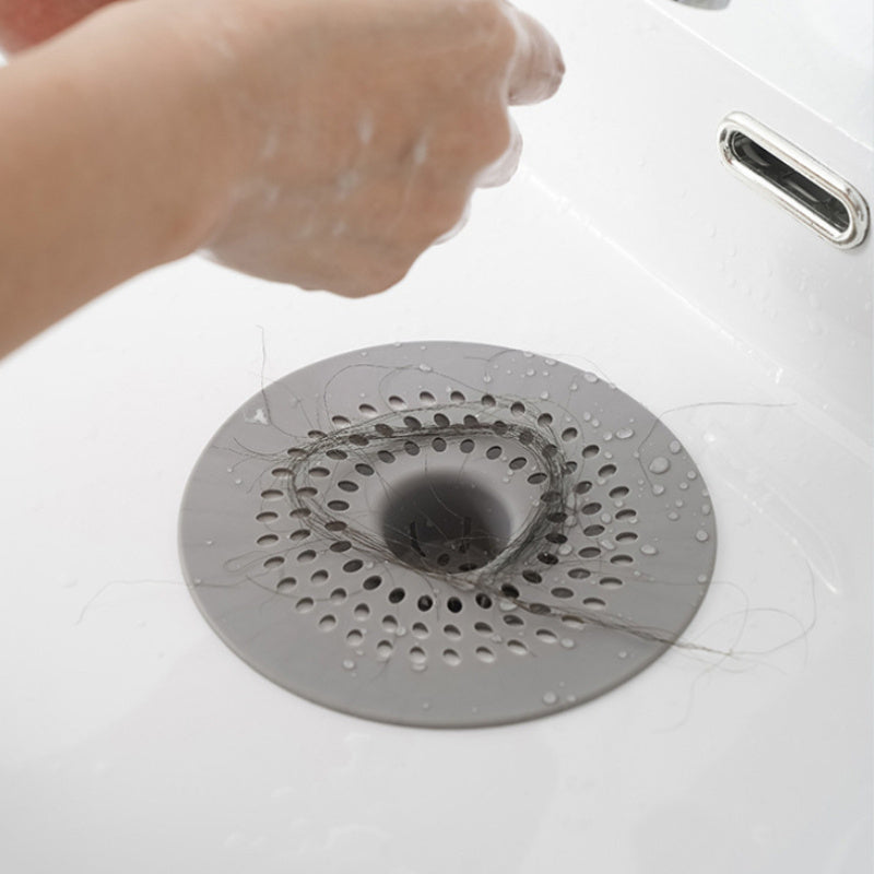 Silicone drain strainer with circular design for shower and kitchen sinks. Available in black or white. Easy to install with drain holes. Ideal for bathroom or kitchen use.