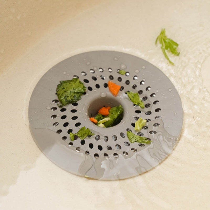 Silicone drain strainer with circular design for shower and kitchen sinks. Available in black or white. Easy to install with drain holes. Ideal for bathroom or kitchen use.