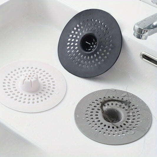 Silicone drain strainer with circular design for shower and kitchen sinks. Available in black or white. Easy to install with drain holes. Ideal for bathroom or kitchen use.