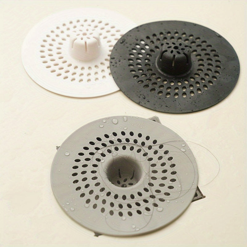 Silicone drain strainer with circular design for shower and kitchen sinks. Available in black or white. Easy to install with drain holes. Ideal for bathroom or kitchen use.