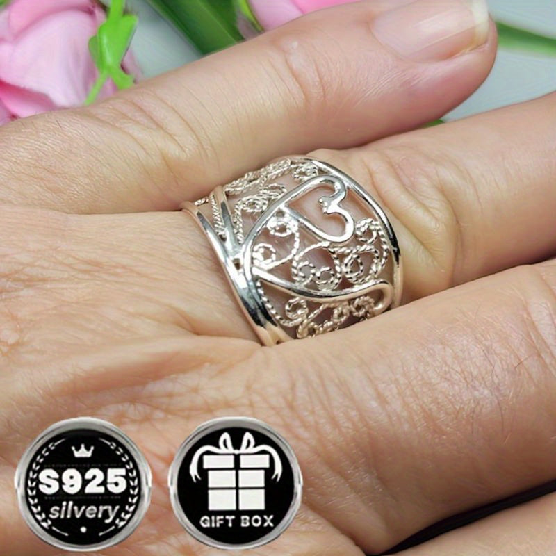 A collection of stylish rings including a delicate filigree design, a bold cigar band, a wide silvery band, a heart-shaped ring made of 925 sterling silver, a thick silvery band, and a bohemian-style ring. This filigree art jewelry is perfect for adding