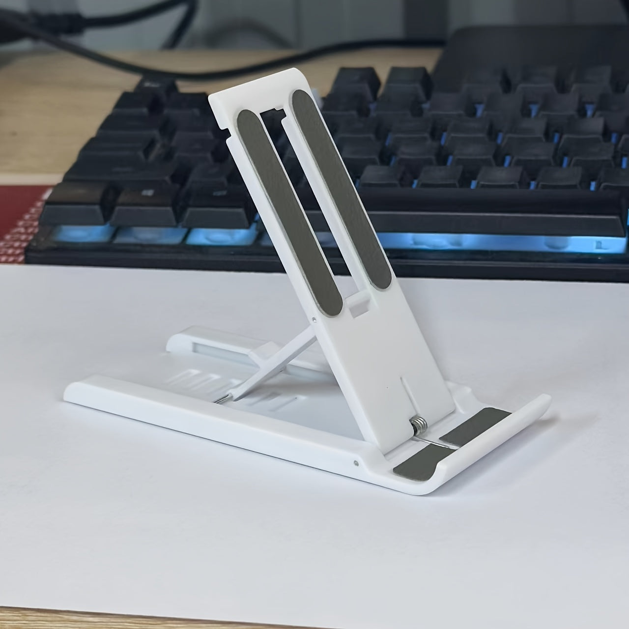 Adjustable foldable phone stand made of multi-functional ABS material, suitable for bedside table or tabletop use with smartphones, tablets, and live streaming support. Not waterproof.