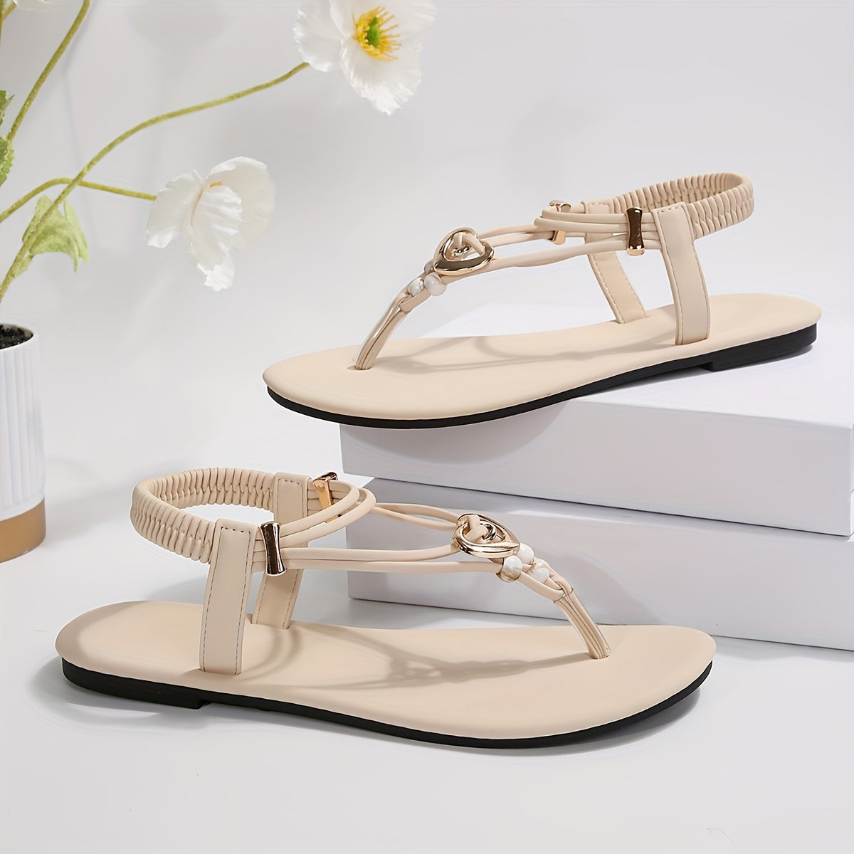 Stylish women's flat sandals with heart charm, braided straps, and pearl accents. Open toe and slip-on design. Perfect for summer beach outings.