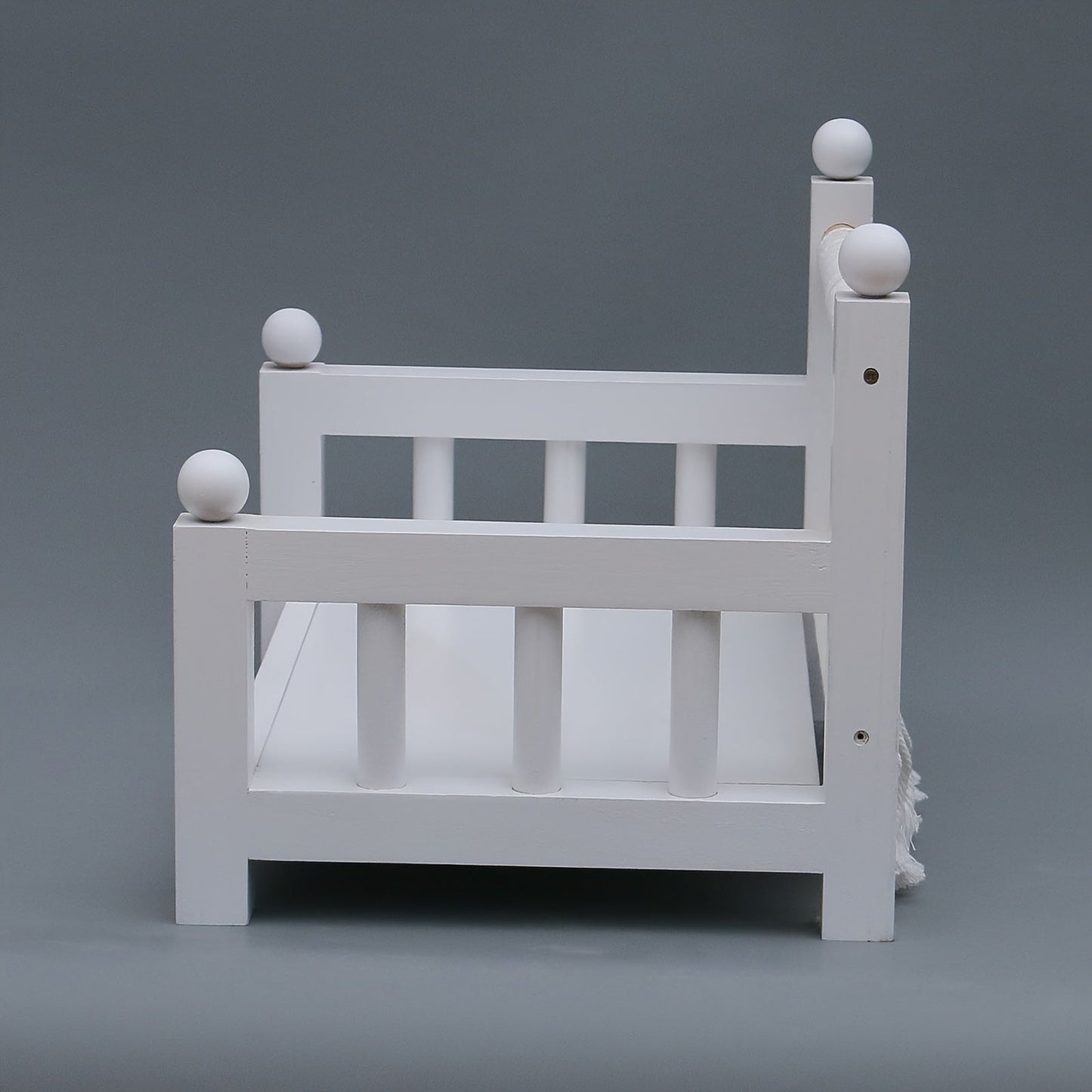 Photography props for baby photos include a white wooden crib bed.