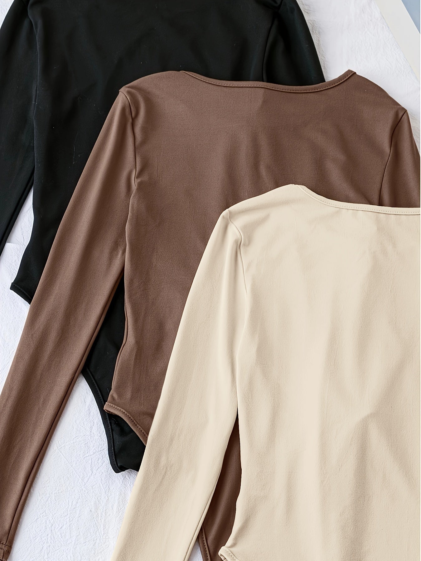 Pack of three solid crew neck long sleeve bodysuits for women. Casual one-piece clothing.