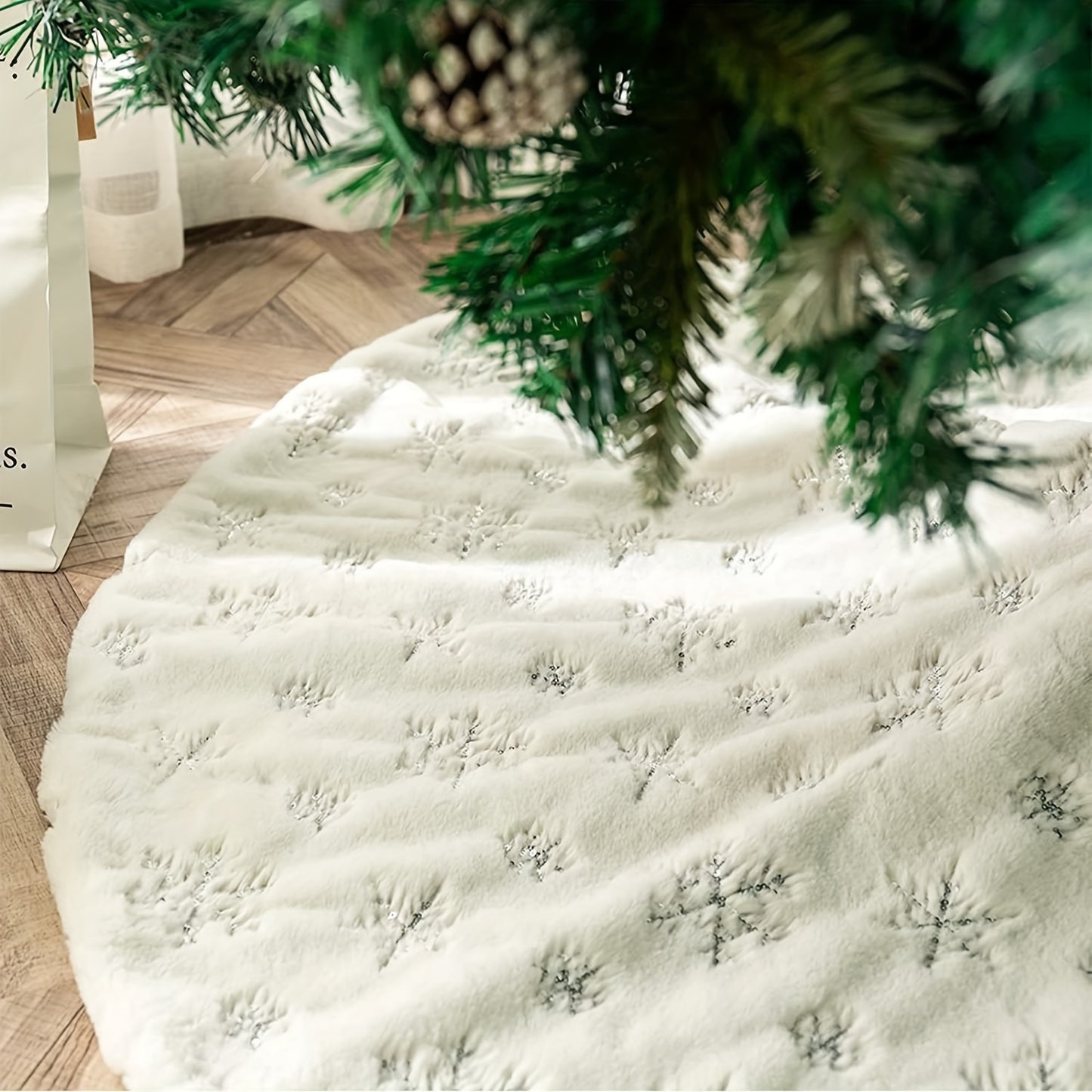 White velvet Christmas tree skirt with golden snowflake embroidery, ideal for Halloween, Christmas, and Valentine's Day. Festive holiday decoration with textured detailing.