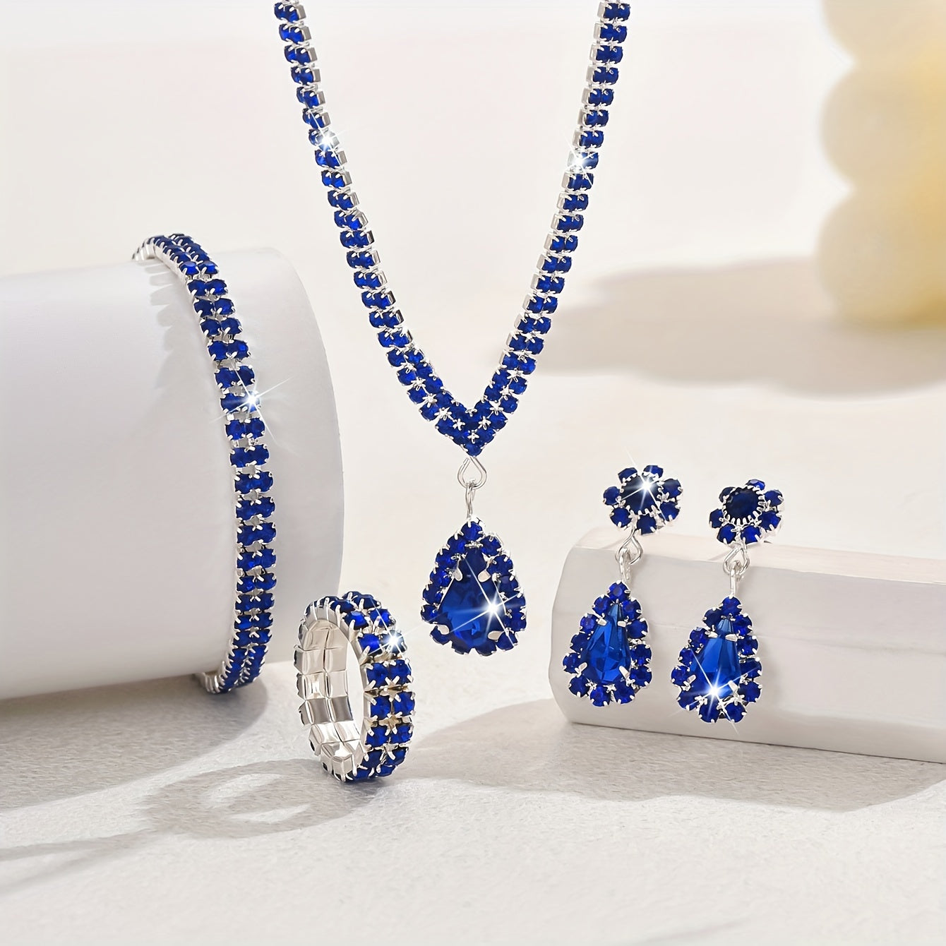 This sophisticated jewelry set features synthetic rhinestones set in silver-plated copper. Included in the set are a necklace, bracelet, earrings, and ring, perfect for weddings and parties. This stunning collection also makes a great Thanksgiving gift.