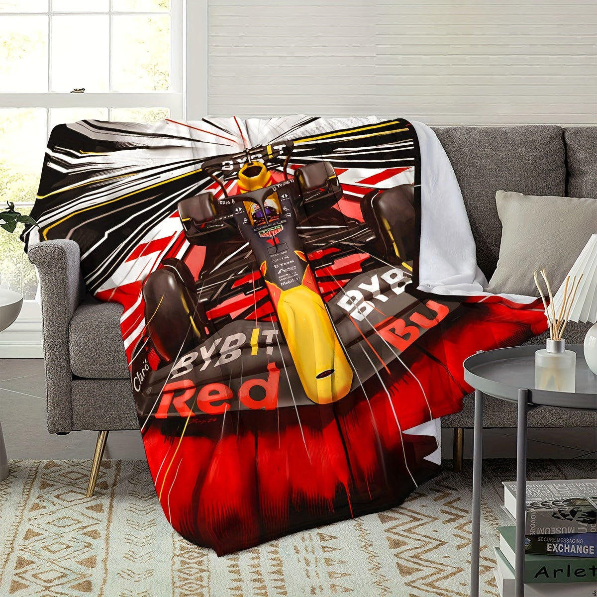 Soft and skin-friendly, this all-season cozy sofa and nap blanket features a dynamic digital design of a vibrant Formula 1 racing car. The blanket is made of flannel and is in red and black with yellow accents.