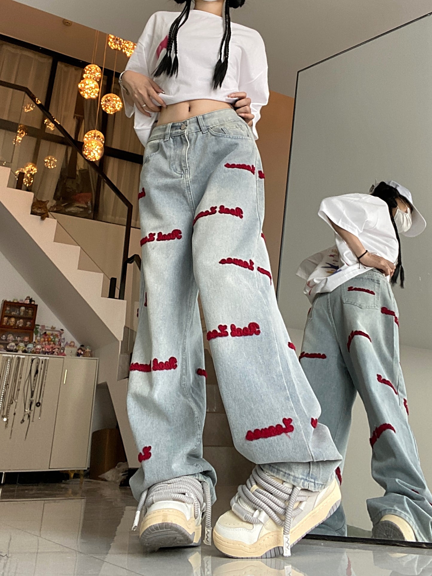 Women's denim jeans with red embroidered lettering, stretch fabric, regular fit, button closure, and washed denim detail. Casual style suitable for all seasons.