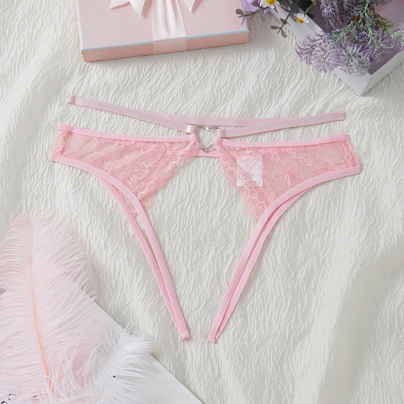 Stylish pink lace thongs for women, featuring a low-rise design with cut-out metal ring detail. Made from a breathable nylon/elastane blend for comfort during intimate moments.