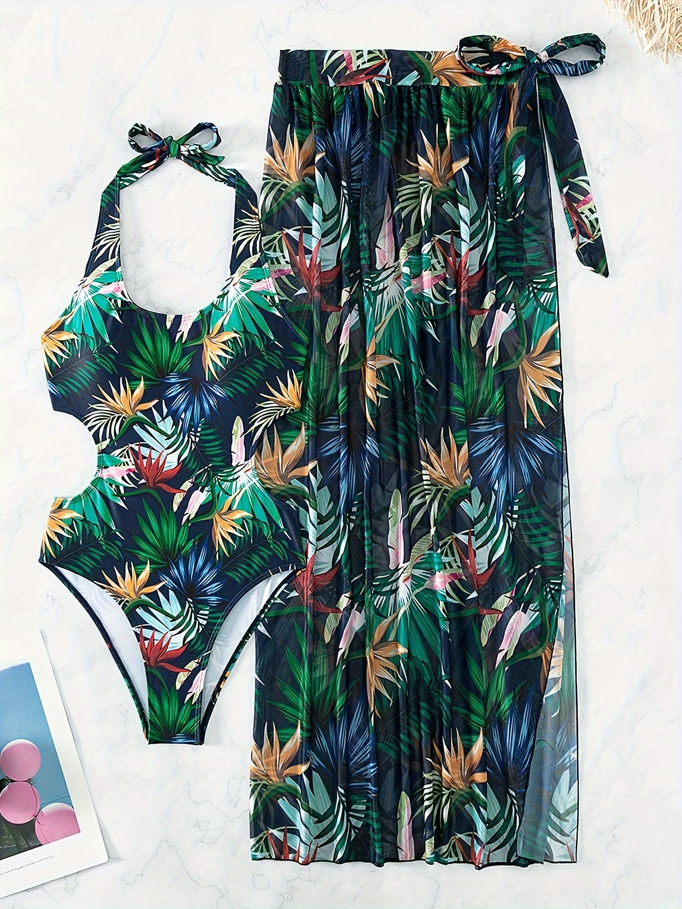 Women's swimwear set with leaf print design, halter top, backless one-piece suit, and matching cover-up skirt.