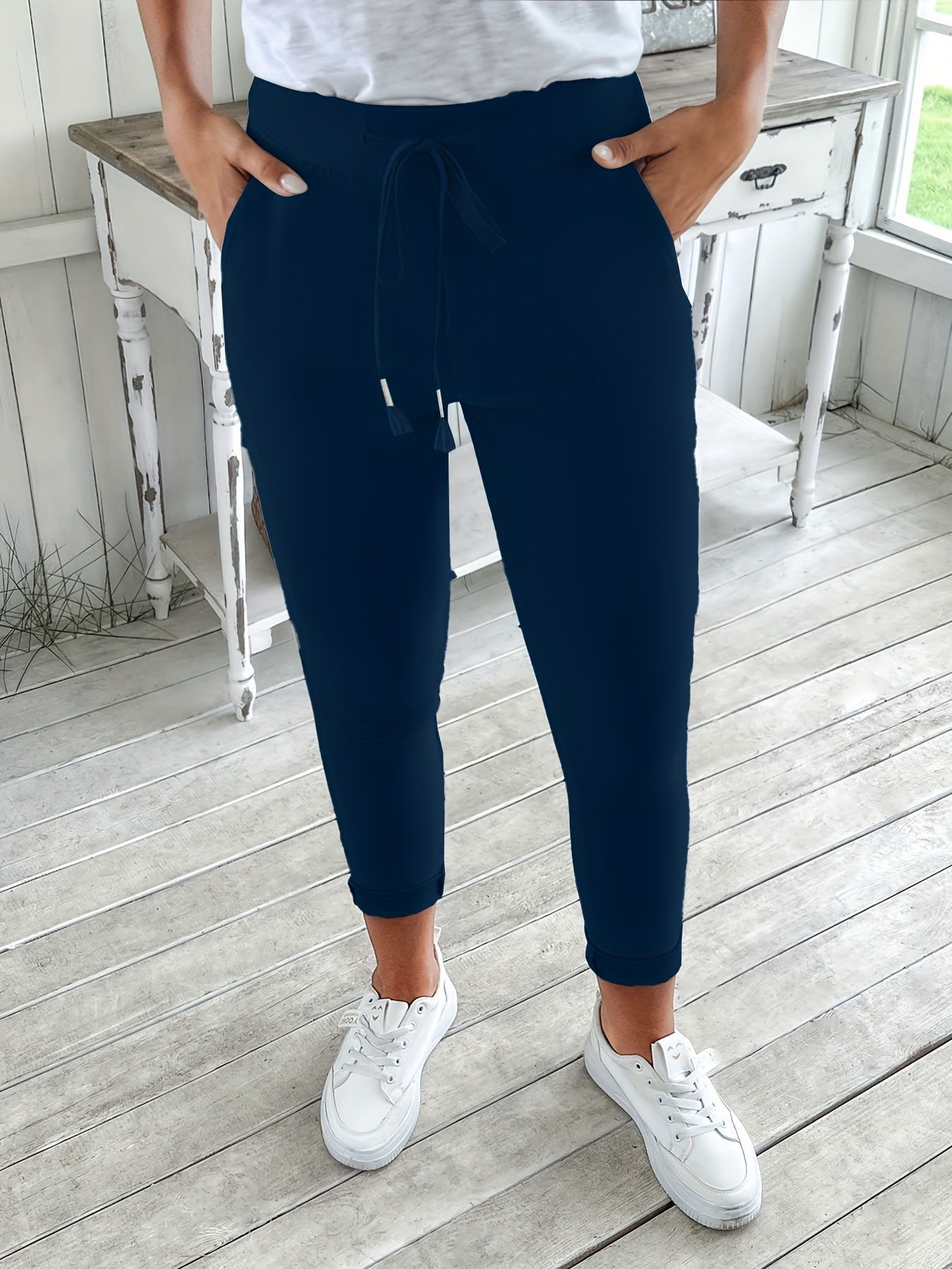 Navy blue drawstring jogger pants for women. Made of stretchy polyester with pockets. Machine washable. Comfortable and adjustable, perfect for all seasons.