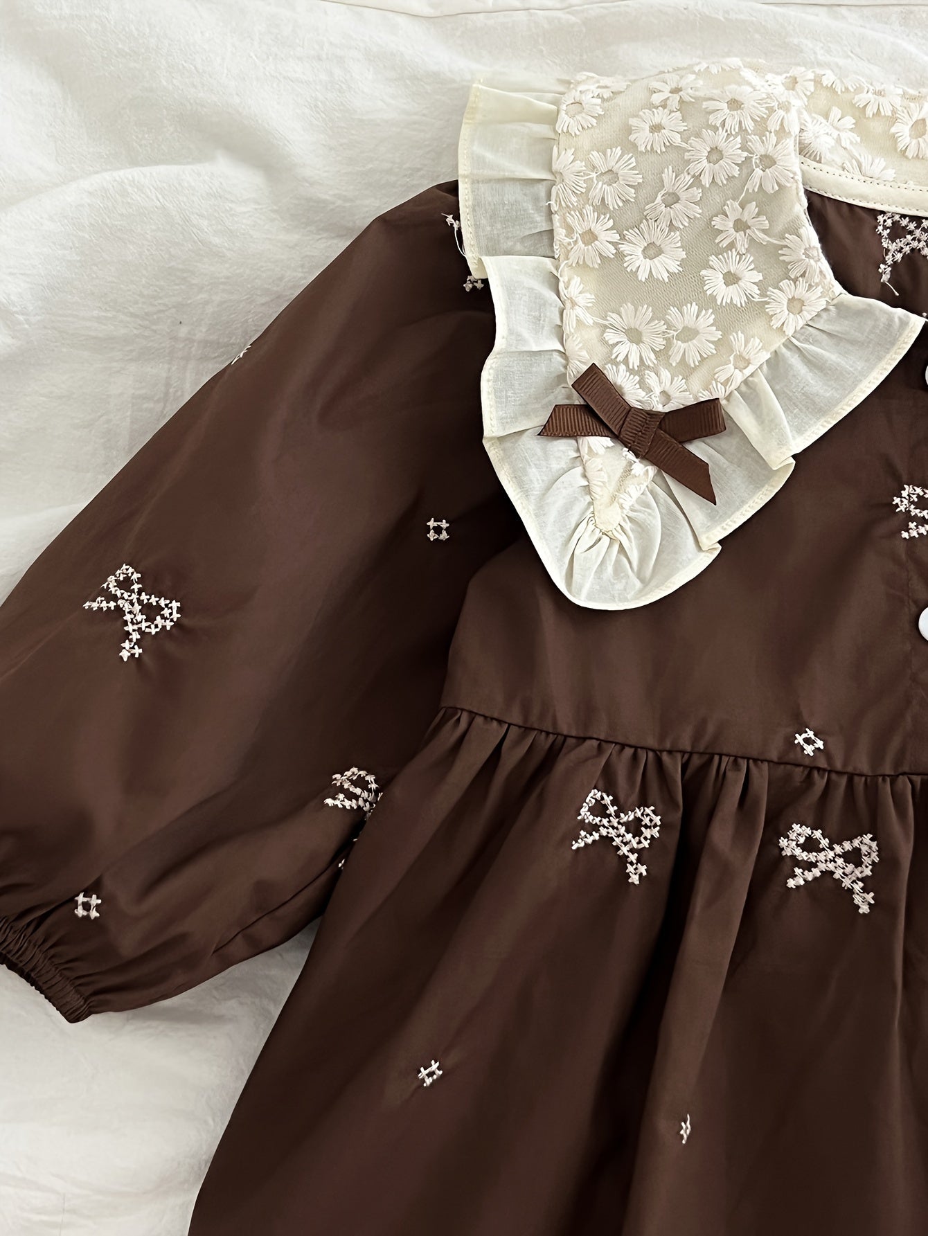 Stylish floral embroidered long-sleeve romper for baby girls, made of cotton with bow detail, ideal for spring/fall and outdoor wear.