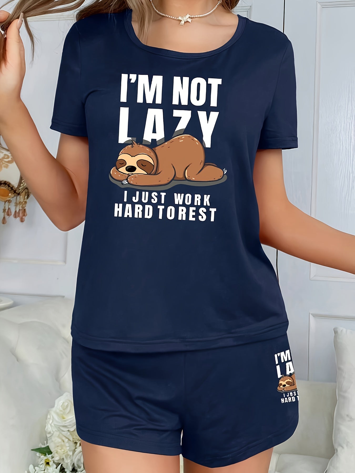 Women's sleepwear set with cute sloth print and slogan, including short sleeve top and elastic shorts.