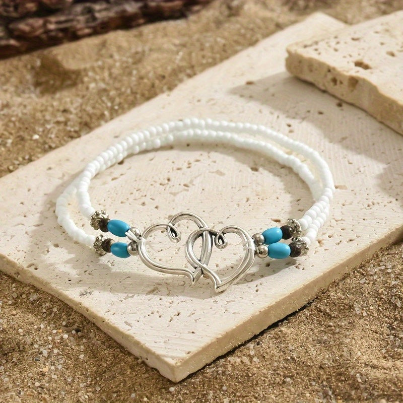 This elegant anklet set features two pieces with double hollowed-out heart shapes adorned with mini seed beads. The design exudes a Bohemian-style charm and is made with stretchy elastic for comfortable wear. A perfect gift for any beautiful woman.