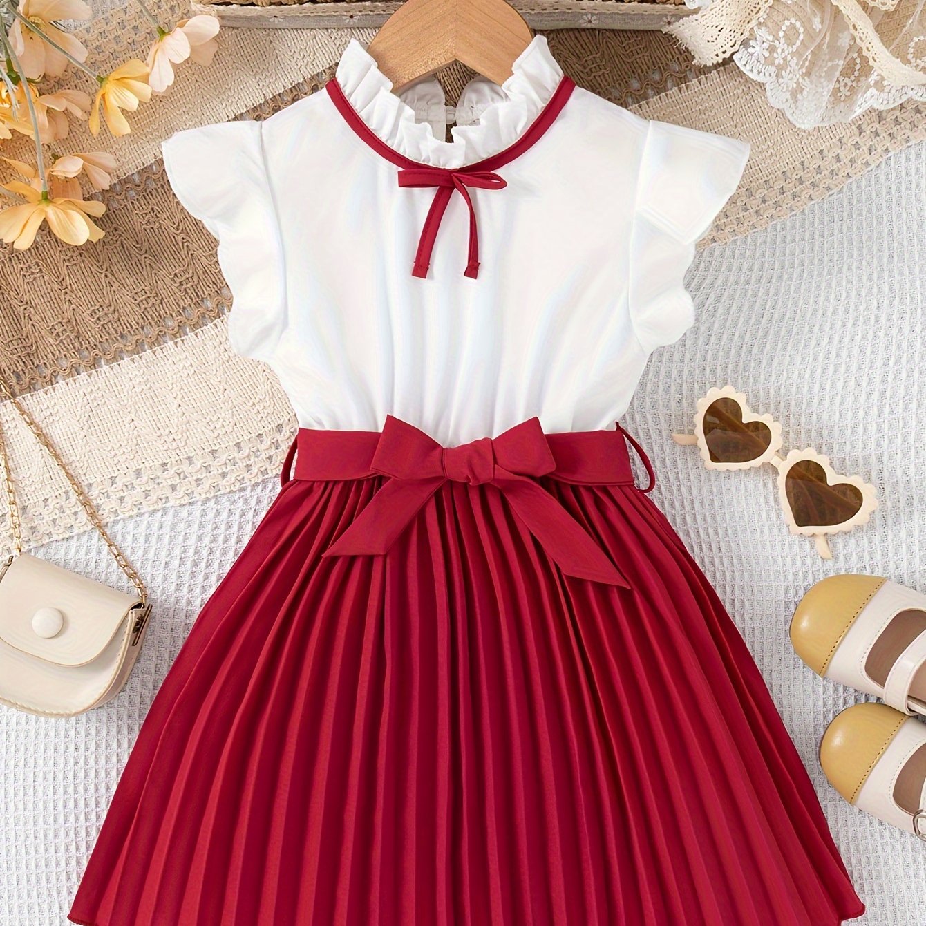 Girls' summer dress with polyester knee-length pleated skirt, stand collar, sleeveless ruffle trim, and bow detail. Features a dressy loose fit with belt for casual outings.