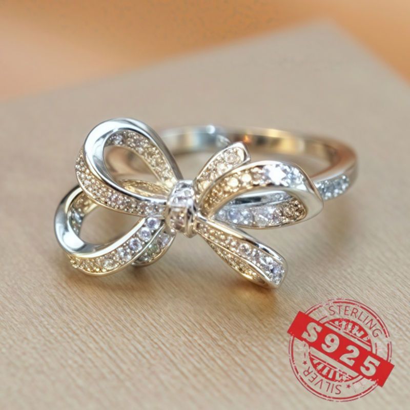 Chic 925 Sterling Silver Ribbon Bow Tie Ring featuring Natural Zirconia, perfect for July Birthdays. This Tribal & Cute style ring is 925 Silver Plated, Tarnish-Resistant, and adorned with Heart-Themed details. Ideal for Daily Wear or Wedding occasions