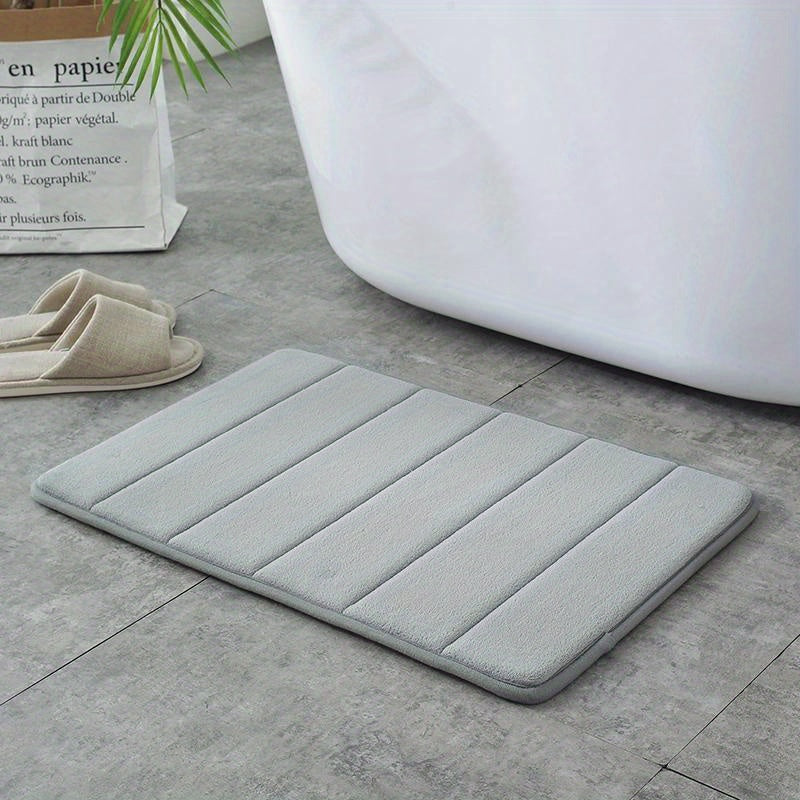 Soft polyester blend bath mat in plush dark gray stripes, featuring a non-slip PVC backing for added safety. Easily machine washable for convenience, this rectangular mat is perfect for adding comfort to your bathroom décor.