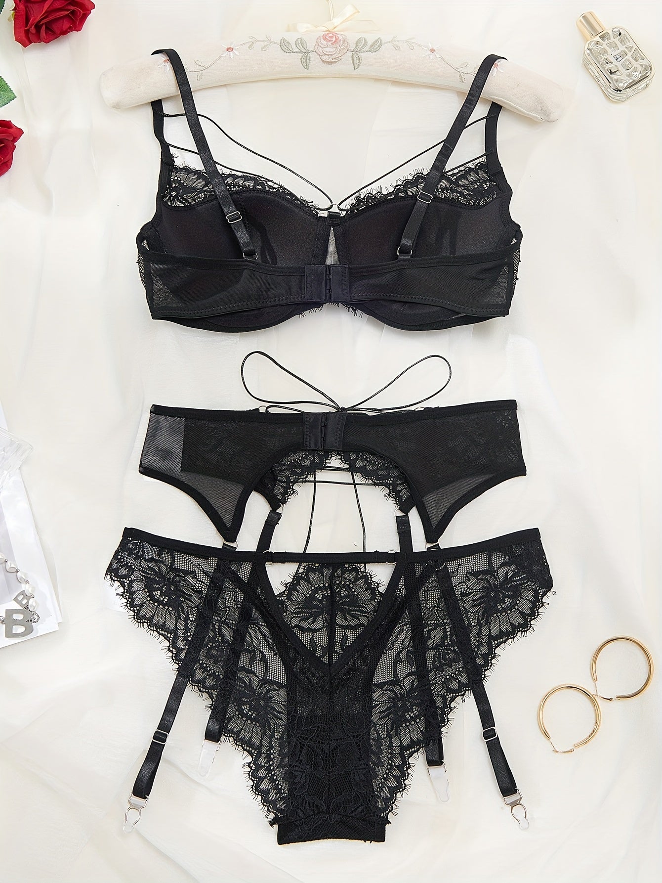 Floral lace lingerie set with bra, panty, and garter belt. Strappy bra, cut-out panties, and lace-up garter belt.