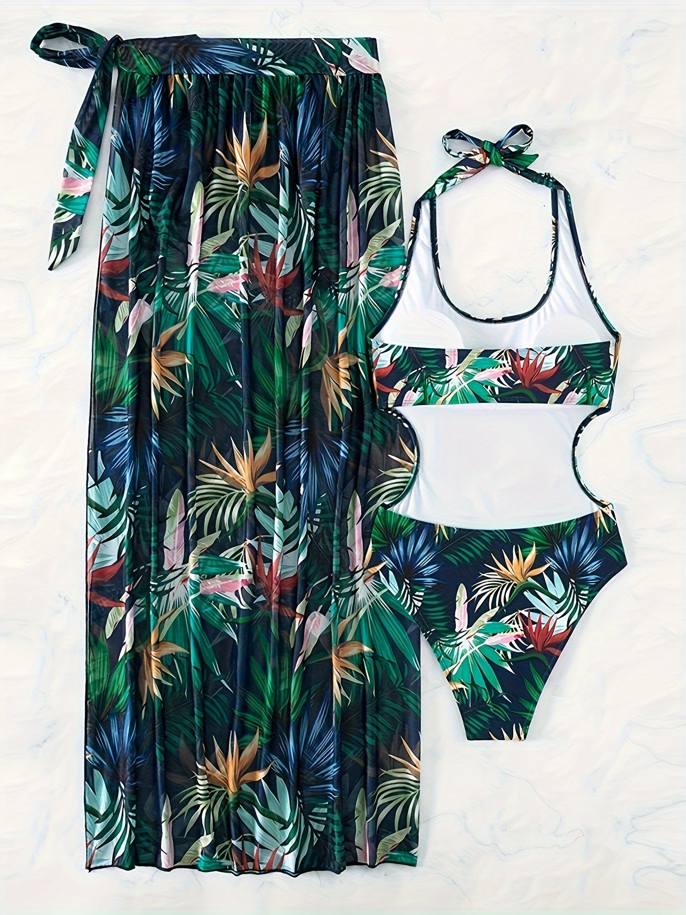 Women's swimwear set with leaf print design, halter top, backless one-piece suit, and matching cover-up skirt.