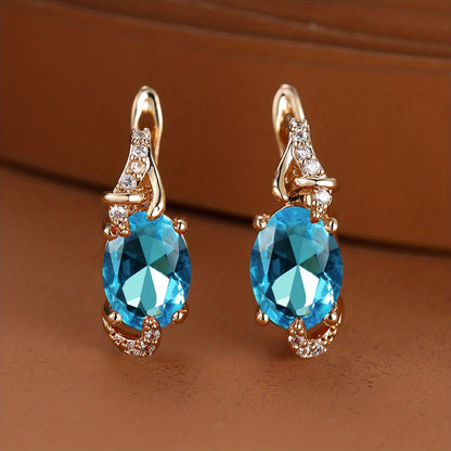 Trendy women's earrings featuring blue, white, red, and pink stones in round and oval cuts. These anniversary claw earrings are plated with 18K gold. Perfect for adding a pop of color to any outfit.