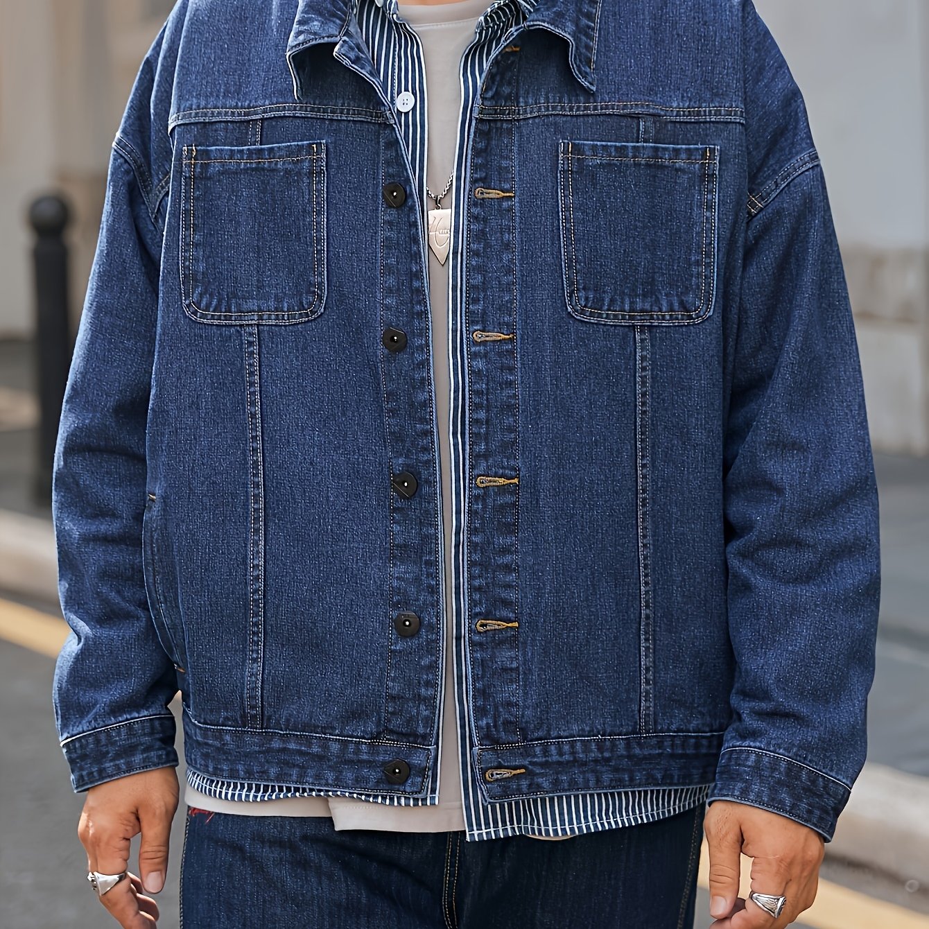 Men's plus size denim jacket in solid washed blue with long sleeves, chest pockets, button-front closure, and loose fit. Machine washable for everyday casual streetwear style with trendy