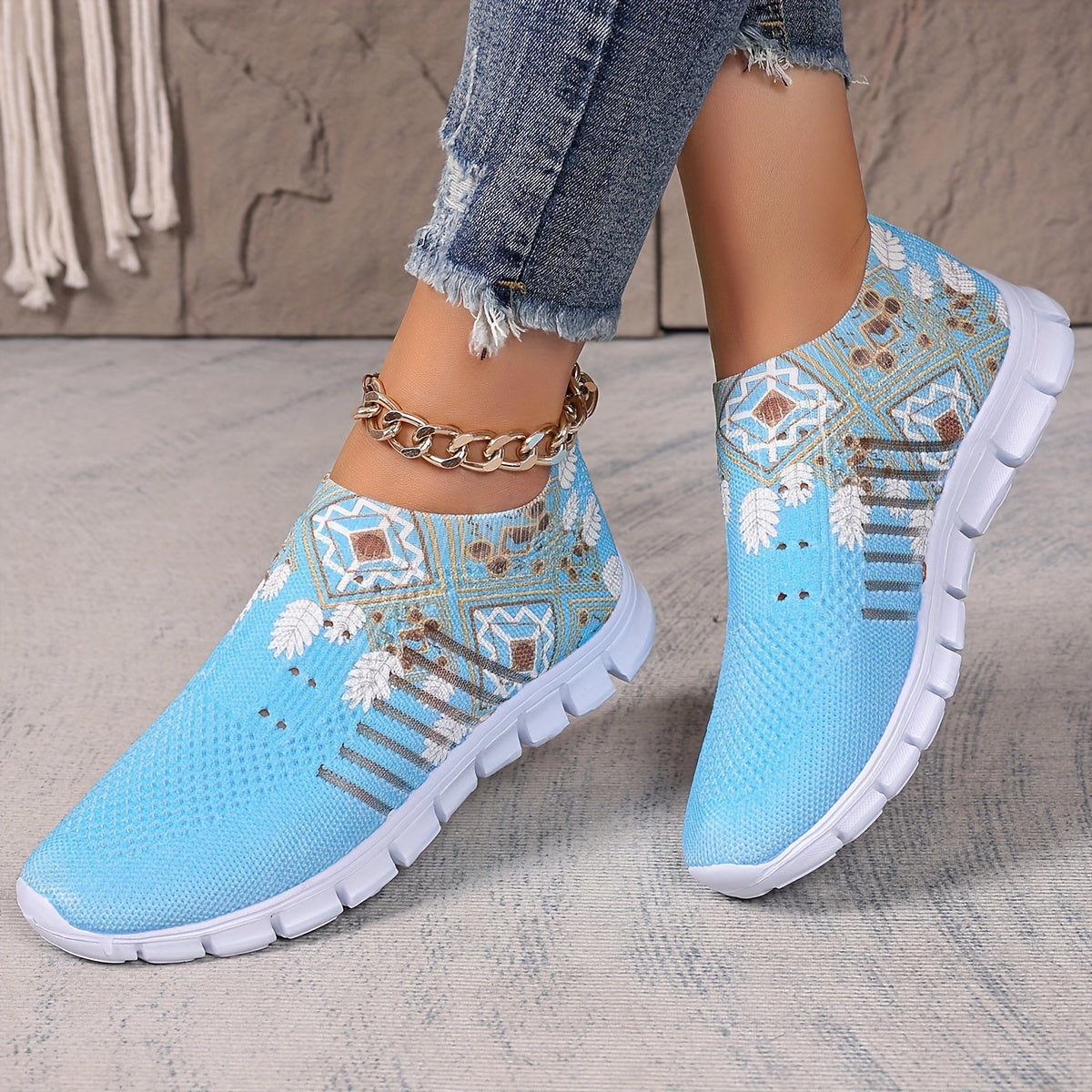 Women's casual slip-on sneakers in blue knit fabric with white floral and geometric patterns, featuring a lightweight EVA sole and breathable low-top design. Perfect for everyday wear with