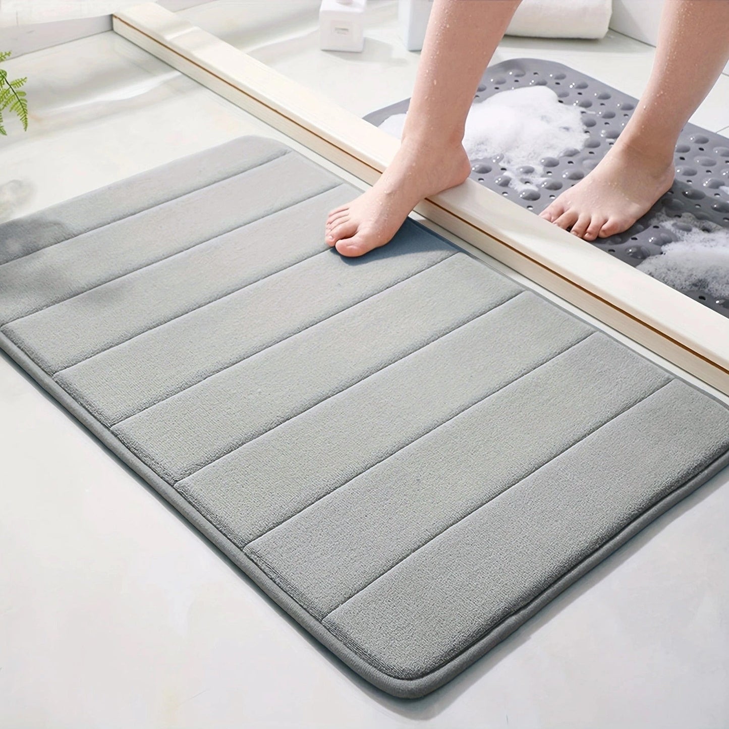 Soft polyester blend bath mat in plush dark gray stripes, featuring a non-slip PVC backing for added safety. Easily machine washable for convenience, this rectangular mat is perfect for adding comfort to your bathroom décor.