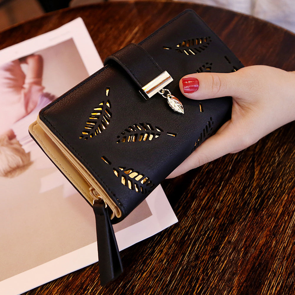 Black synthetic leather women's wallet with golden leaf design, featuring card holders, coin pouch, and snap closure.