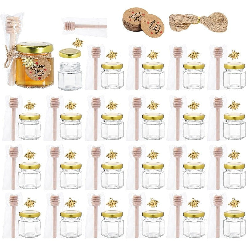 Tiny honey jars with wooden dipsticks, hexagonal glass containers topped with golden lids, embellished with charming golden bee accents, and accented with decorative jute perfect for weddings, baby showers, and party favors.