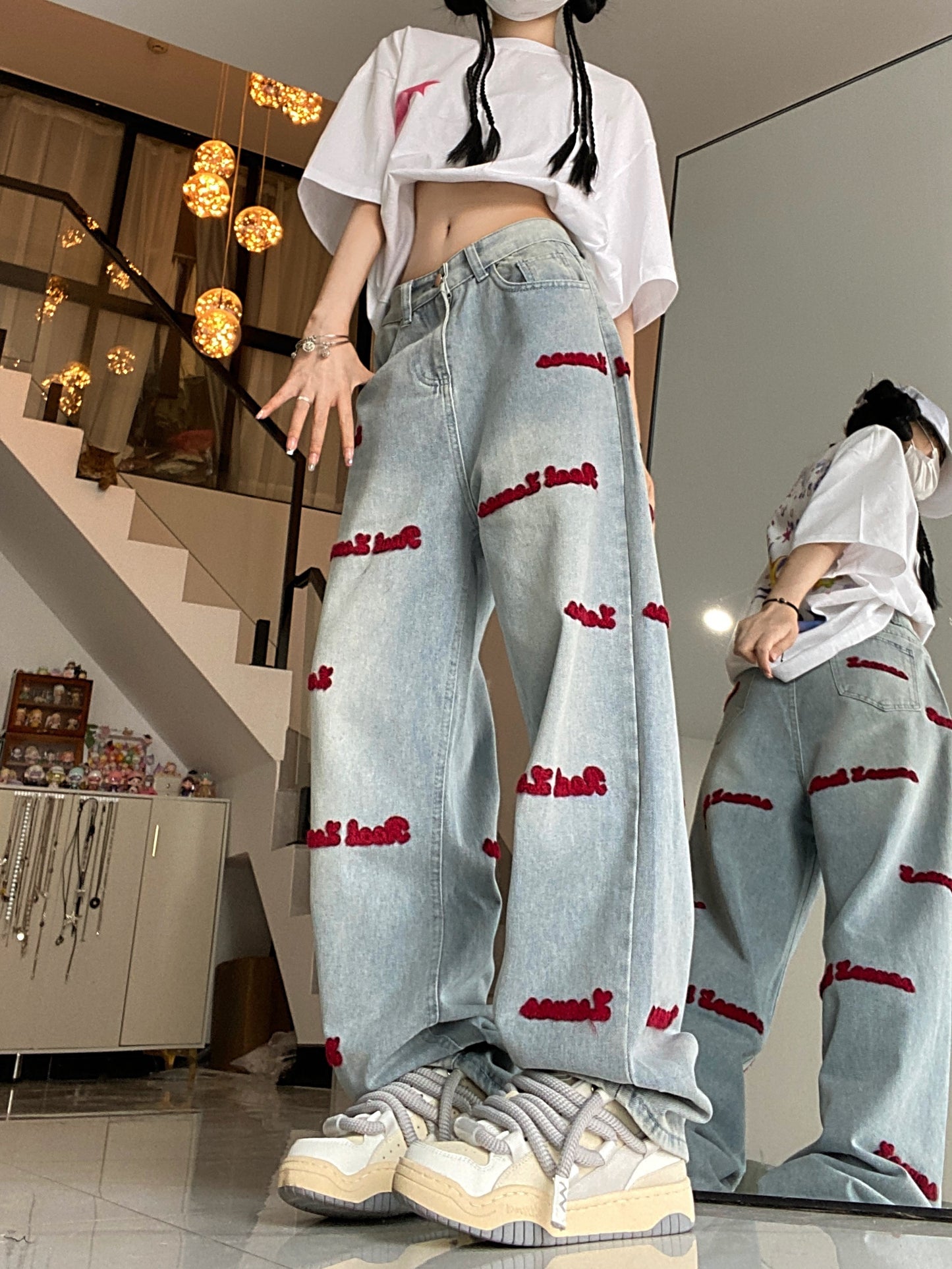 Women's denim jeans with red embroidered lettering, stretch fabric, regular fit, button closure, and washed denim detail. Casual style suitable for all seasons.