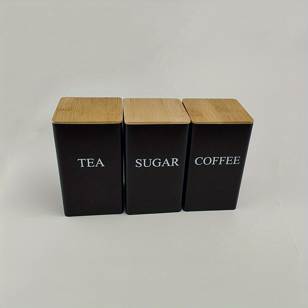 Three square metal canisters with wooden lids - one for tea, one for sugar, and one for coffee.