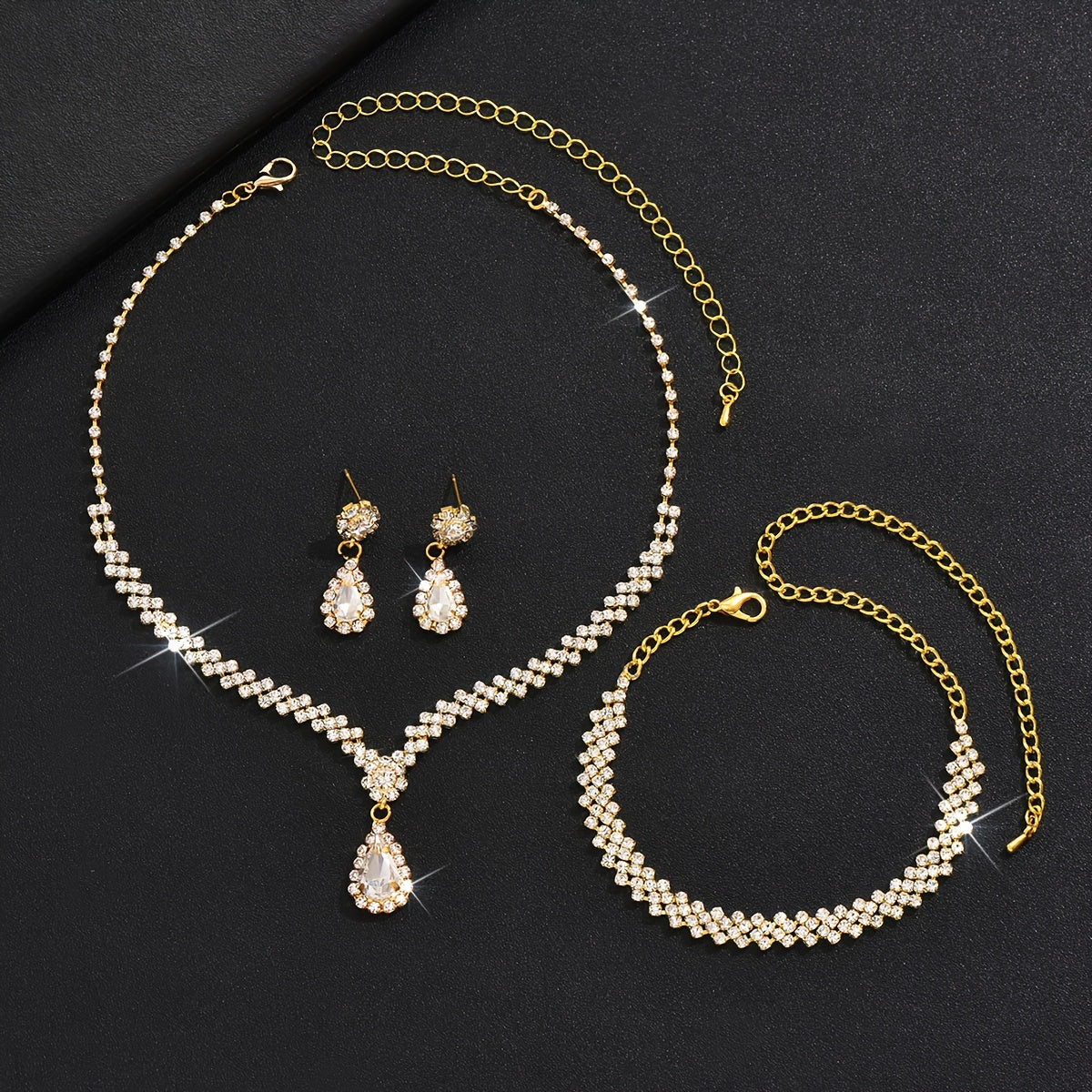 1 set of trendy female wedding decor jewelry, including dangle earrings, a necklace, and a bracelet all featuring a water drop pendant design with rhinestones inlaid.