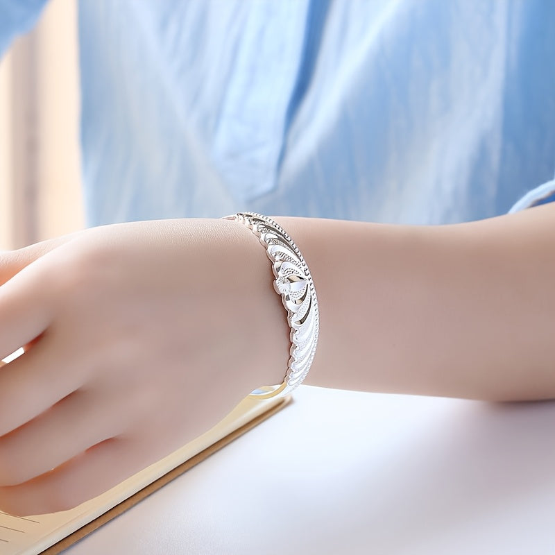 A stunning silver bracelet for women with a crown design, adorned with delicate flowers and shimmering stars. The bracelet features an elegant open mouth clasp for easy wearing.