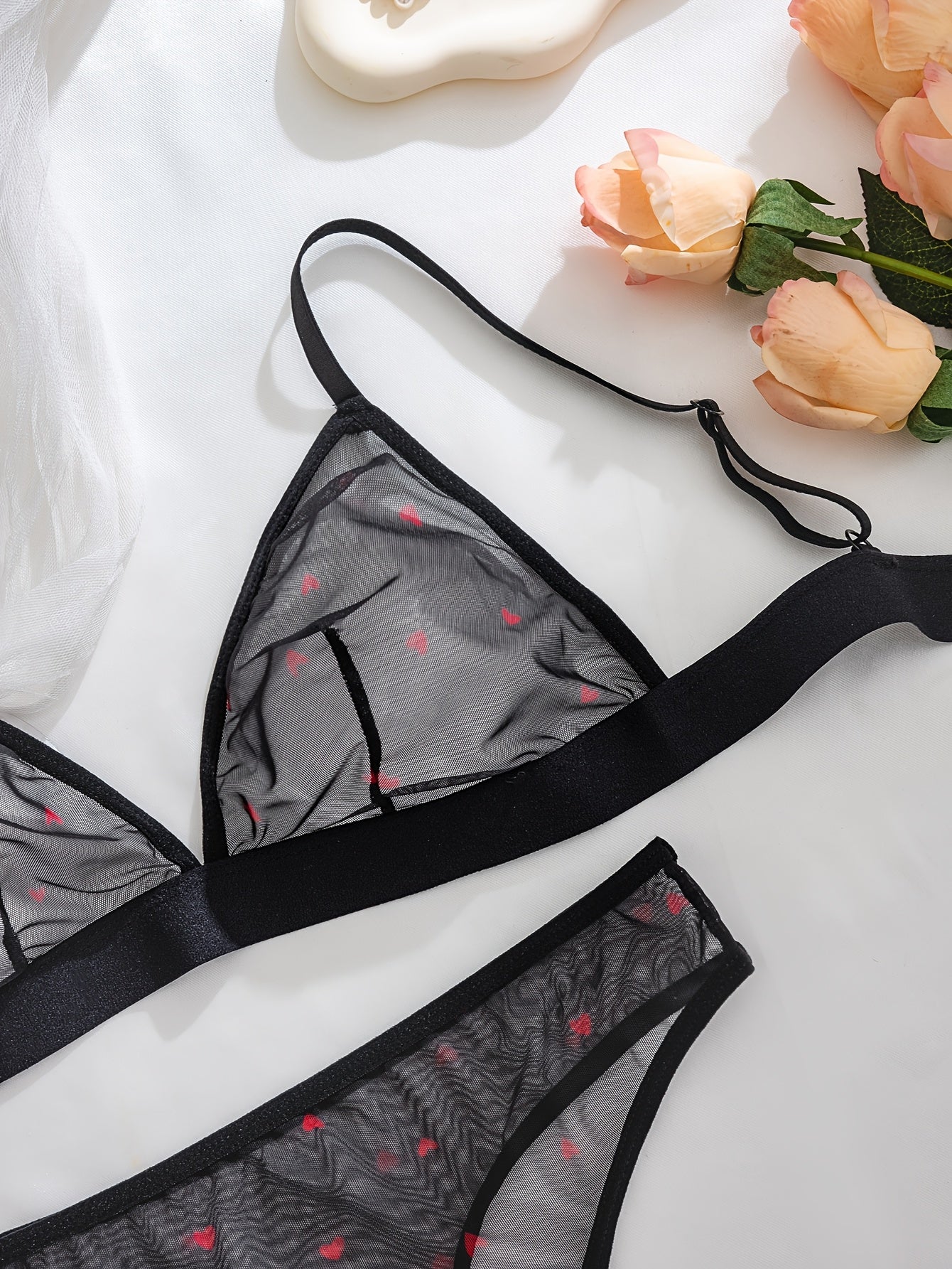 Black and red heart mesh lingerie set includes sheer back bra and low-rise thong in breathable polyester blend. Romantic, backless design with adjustable straps and quality workmanship.