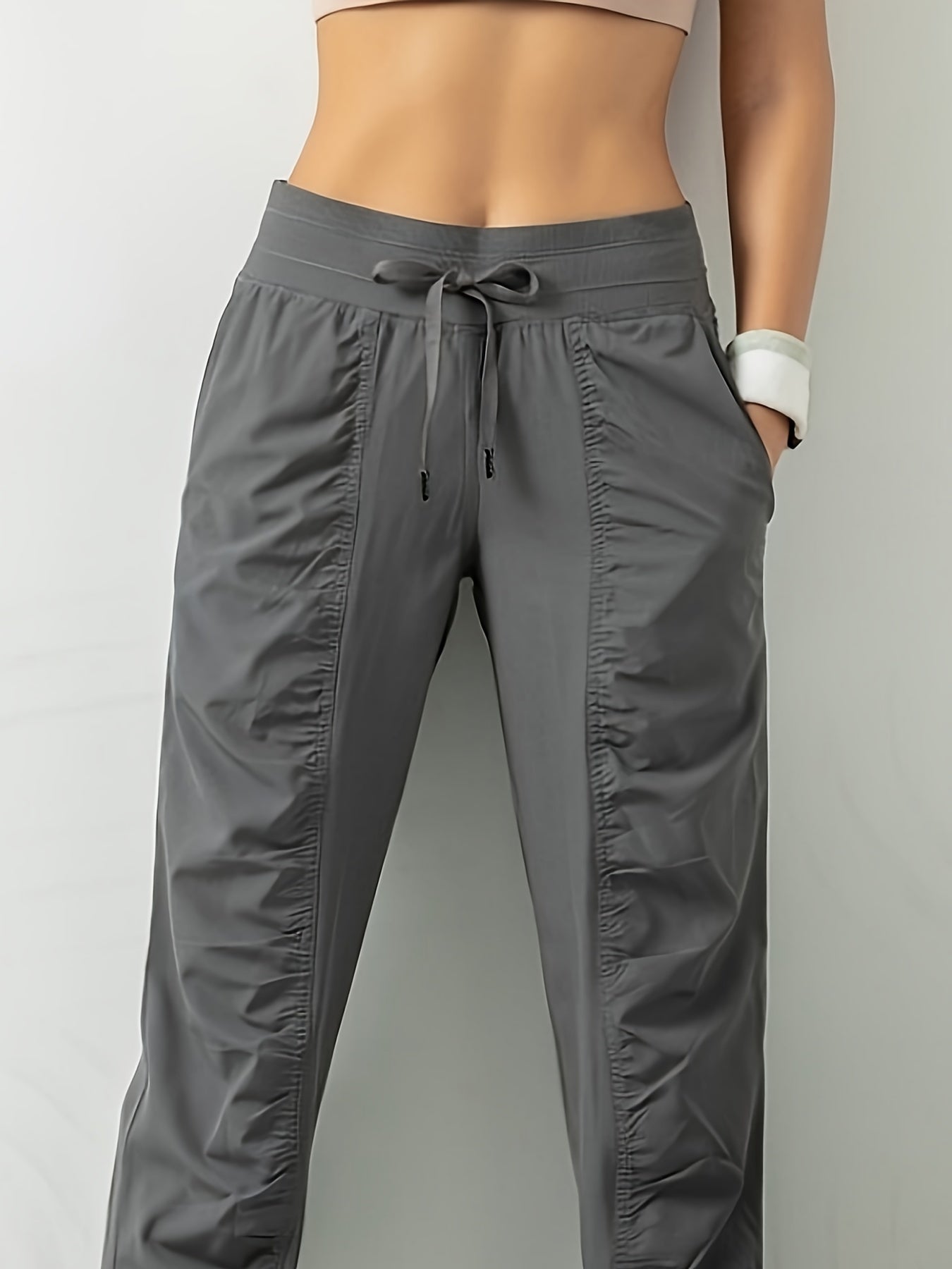 Women's solid color sports pants with drawstring waist, quick drying material, and side pockets for casual comfort.