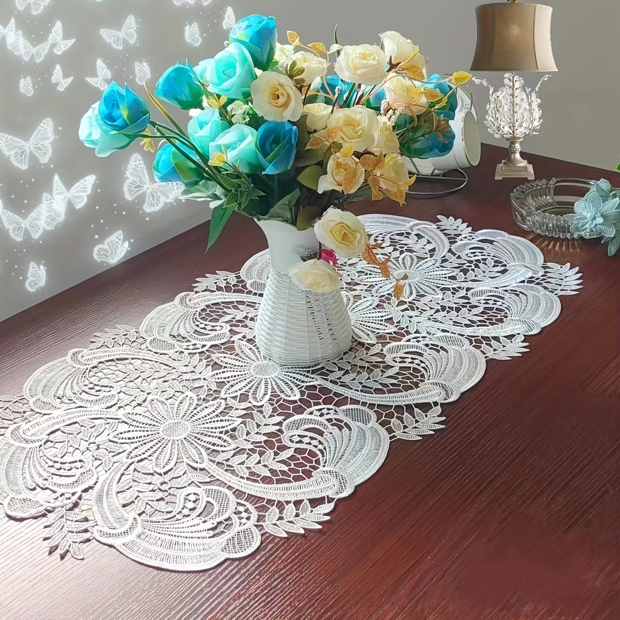 White velvet lace oval table runner with floral pattern, perfect for holiday table setting. Butterfly motif on decorative fabric for dining and home decor.