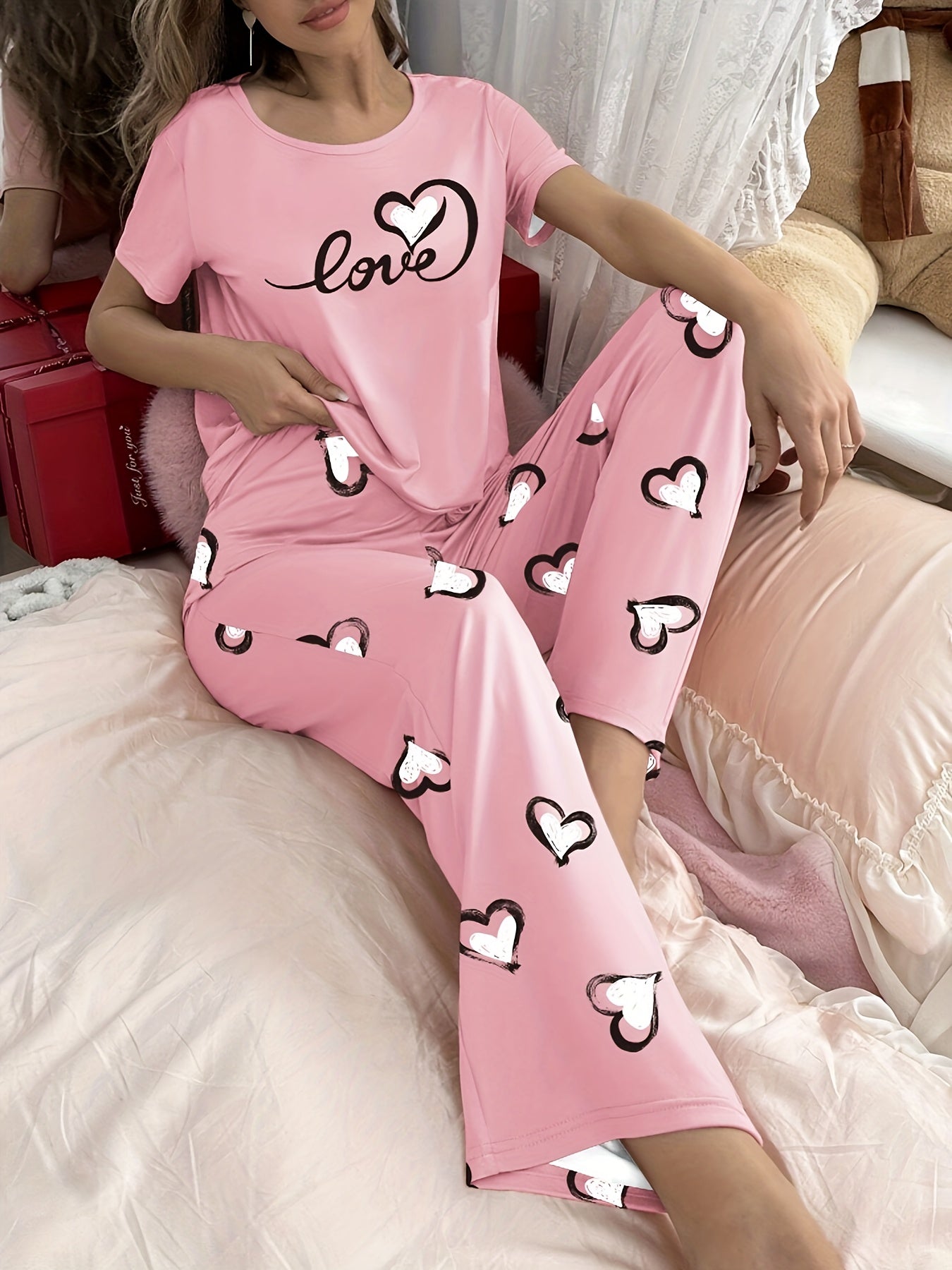 Stylish pink heart print pajama set for women with comfy short sleeve top and long pants, made of breathable polyester blend fabric.