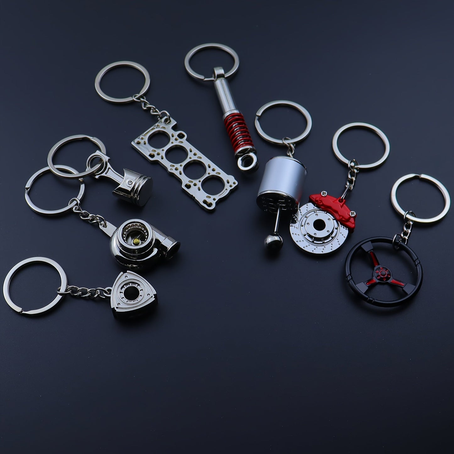 Keychains for creative car modifications, including piston, brake disc, gear, turbocharger, small rotor, shock absorber, engine blade, and steering wheel designs. Perfect for car enthusiasts and as a unique gift.