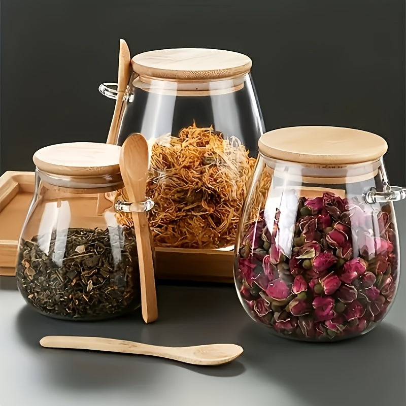 Glass tea jar with wooden spoon and lid, ideal for storing loose tea leaves and herbs. Measures 10cm/3.9in x 6.5cm/2.6in with a capacity of 350ml. Adds a touch of charm to your kitchen and dining room decor.