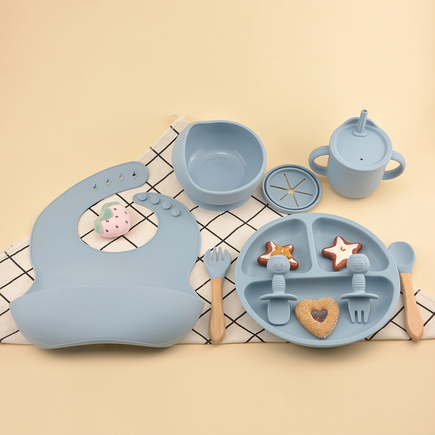 This set includes 9 pieces of feeding cutlery made of food-grade silicone, featuring a silicone bib, suction dinner plate, suction bowl, wooden handle silicone spoon and fork, food supplement spoon and fork, two-in-one drinking training cup, and eating