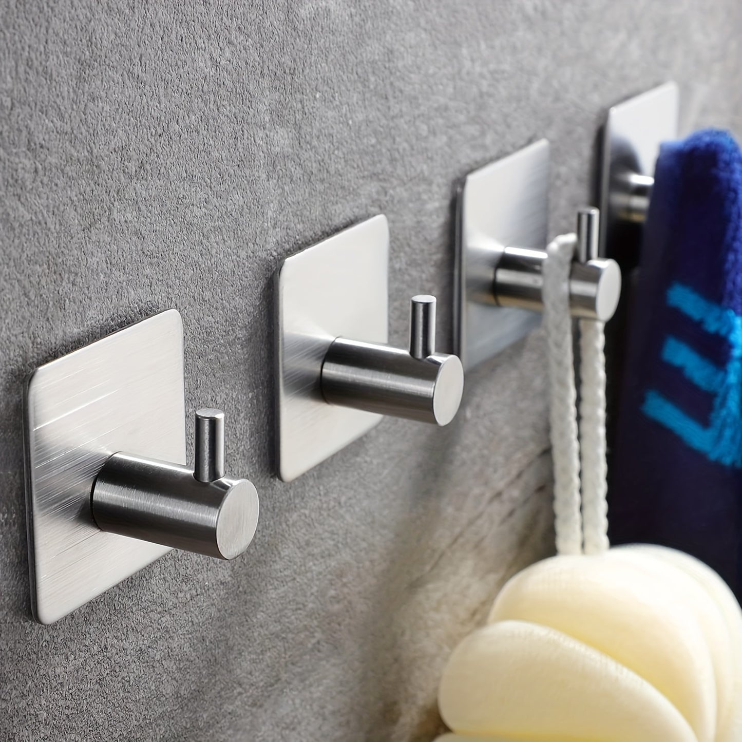 Four-pack of durable stainless steel hooks for robes and towels, easy to install on walls for bathroom and bedroom organization.