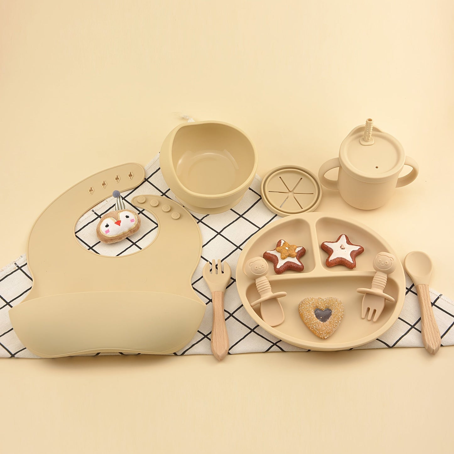 This set includes 9 pieces of feeding cutlery made of food-grade silicone, featuring a silicone bib, suction dinner plate, suction bowl, wooden handle silicone spoon and fork, food supplement spoon and fork, two-in-one drinking training cup, and eating