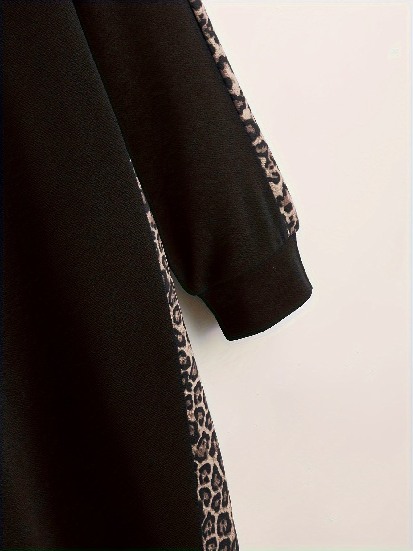 Black hoodie with leopard print accents, long sleeves, drawstring hood, and pockets. Made from polyester knit, oversized fit.