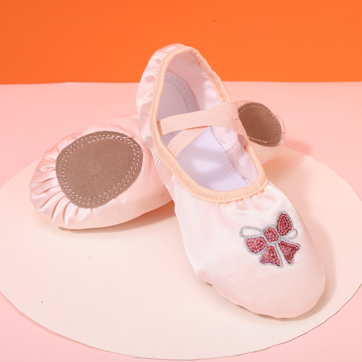 Girls’ ballet dance shoes with sparkling sequin and embroidered bow detail, soft sole, breathable canvas slip-ons. Available in pink and peach.