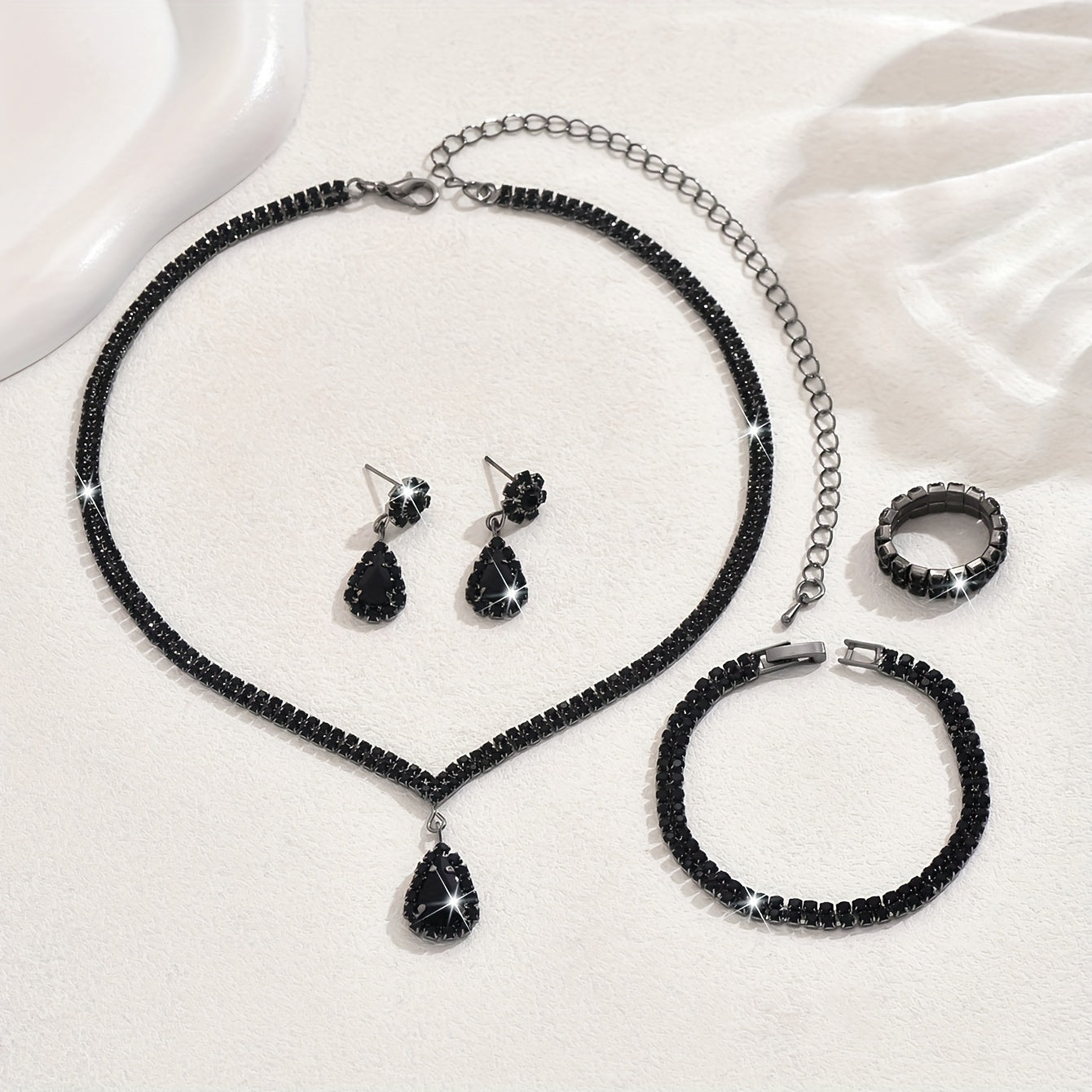 This sophisticated jewelry set features synthetic rhinestones set in silver-plated copper. Included in the set are a necklace, bracelet, earrings, and ring, perfect for weddings and parties. This stunning collection also makes a great Thanksgiving gift.