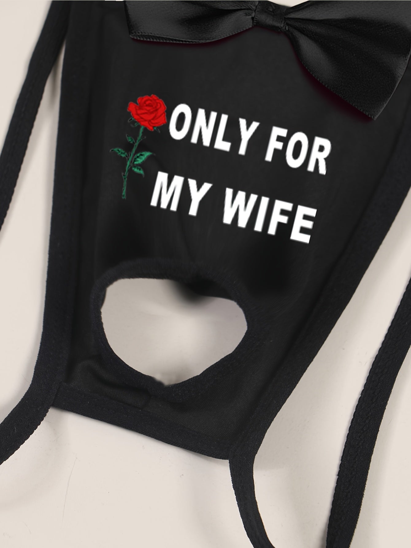 Men's sexy black thong with front cut-out and bow detail, featuring "ONLY FOR MY WIFE" red rose print. Made with comfortable, breathable polyamide (90%) and elastane (10%) knit fabric.